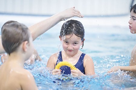 Kinder bespritzen sich im Becken mit Wasser.