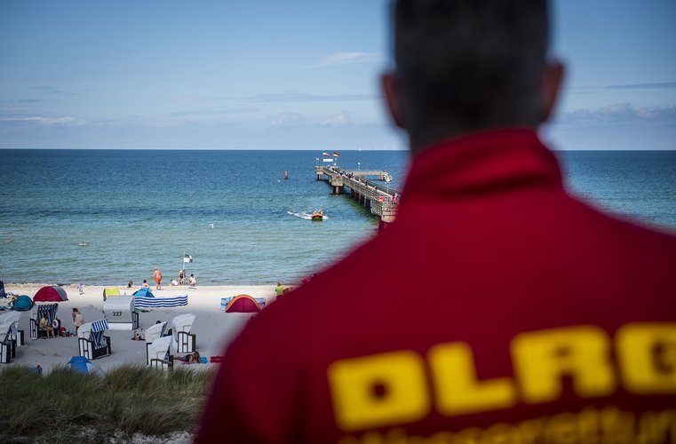 Sicht über die Schulter eines Rettungsschwimmers auf den Strand und das Meer.